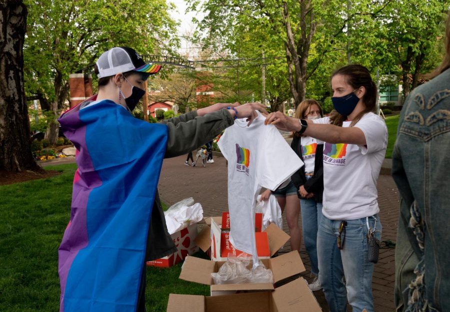 A pride t-shirt is handed from one person to another