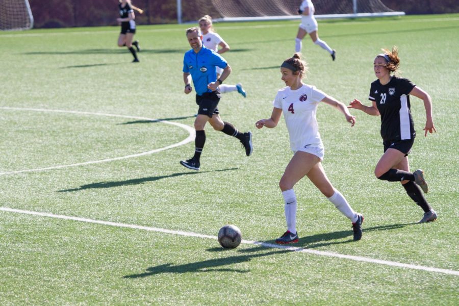 Forward Lauren Forster dribbles the ball past Western Oregon Wolves forward Maddy Topaum.