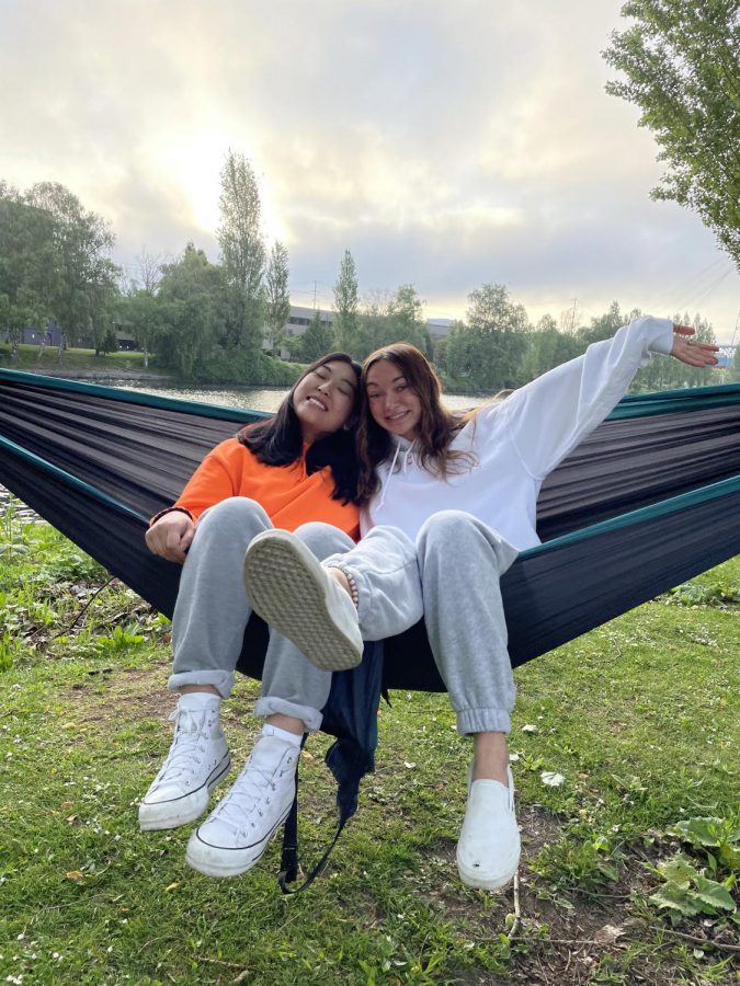 Cara Hiroyasu (left) and Bree Hastin (right) sitting together enjoying a sunrise in hammocks by the canal.
