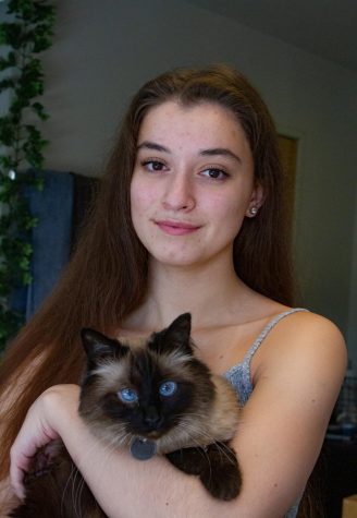 Girl stands with a cat in her arms