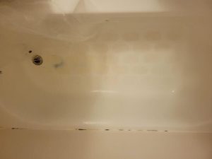 A bathtub in the apartments with a concerning stain blue stain. 