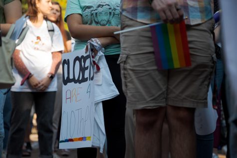 A student holds a rainbow flag while another holds a sign saying closets are for cloths during a demonstration in Martin Square at Seattle Pacific University in Seattle, Wash., on Sept. 12, 2022.