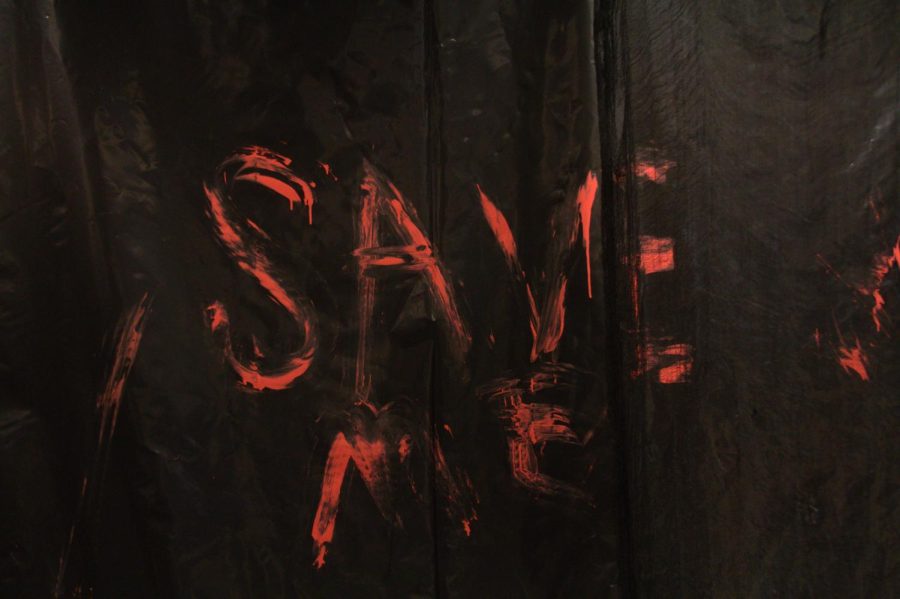 A tarp with the words  save me painted in fake  blood hangs in Weter Hall.
