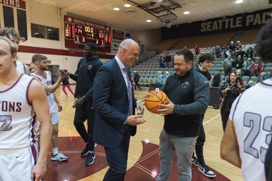 Seattle Pacific Athletic Director Jackson Stava hands Mens Basketball Head Coach Grant Leep the game ball from his 100th win at the helm of the Falcons.