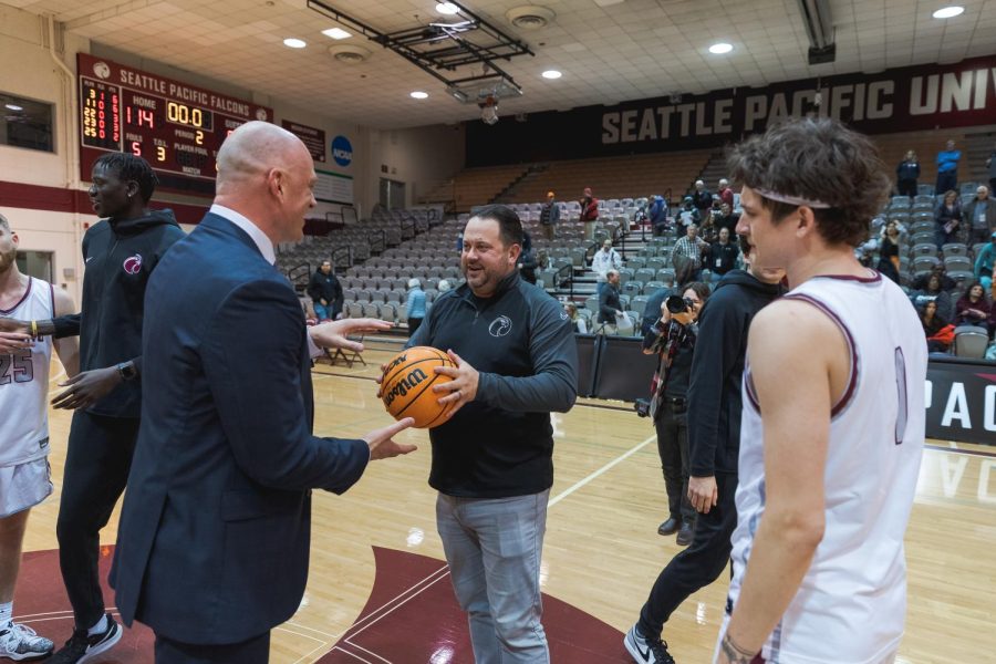 xFormer SPU athletic director Jackson Stava (center) hands coach Grant Leep the game ball from his 100th win at the helm of the SPU mens basketball team as Zack Paulsen (right) looks on.
