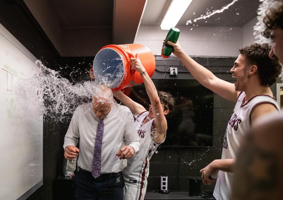 Zack Paulsen (center) and Trace Evans (right) dump water on to mens basketball head coach Grant Leep as he enters the locker room after recording his 100th career win. The falcons defeated Douglas College 114-67 on Nov. 22, 2022.