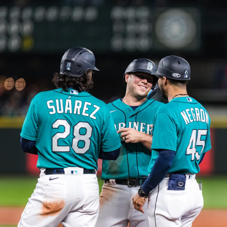 Seattle Mariners third baseman Eugenio Suarez (28), Seattle Mariners first baseman Ty France (23) and Seattle Mariners first base coach Kristopher Negrón (45) meet at first base during a pitching change during a baseball game Friday, April 14, 2023, in Seattle. The Mariners won 5-3.