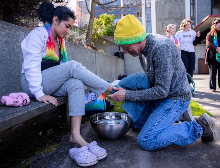 Dr. Kevin Neuhouser washes the foot of Julia Flores during a foot washing ceremony at a day of silence demonstration outside of Demeray Hall on Friday, April 14, 2023. 