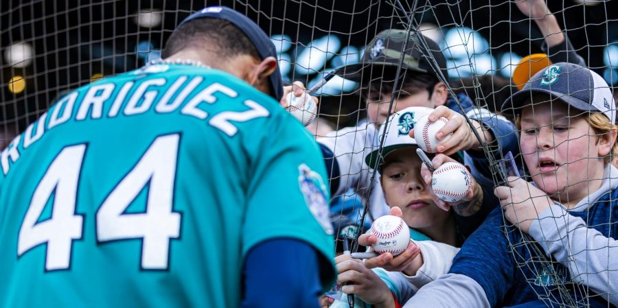Young fans open a gap in the foul ball netting and to try and get a signature from Seattle Mariners center fielder Julio Rodriguez (44) ahead of a baseball game Friday, April 14, 2023, in Seattle. The Mariners won 5-3.