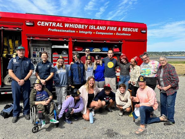 Sydney Lorton (bottom center) poses for a photo with her campers and the Whidbey Island Fire Department on Whidbey Island on Saturday, July 29, 2023. (Courtesy of Sydney Lorton)