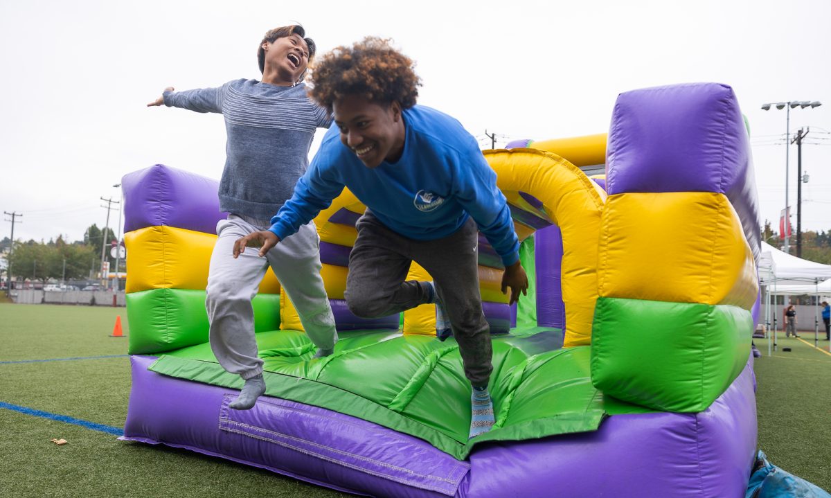 Gum Nau (left) and Brandon Lewis (right) fly across the finish line of the inflatable obstacle course at Second Saturday on Wallace Field on Saturday, Sept. 23, 2023.