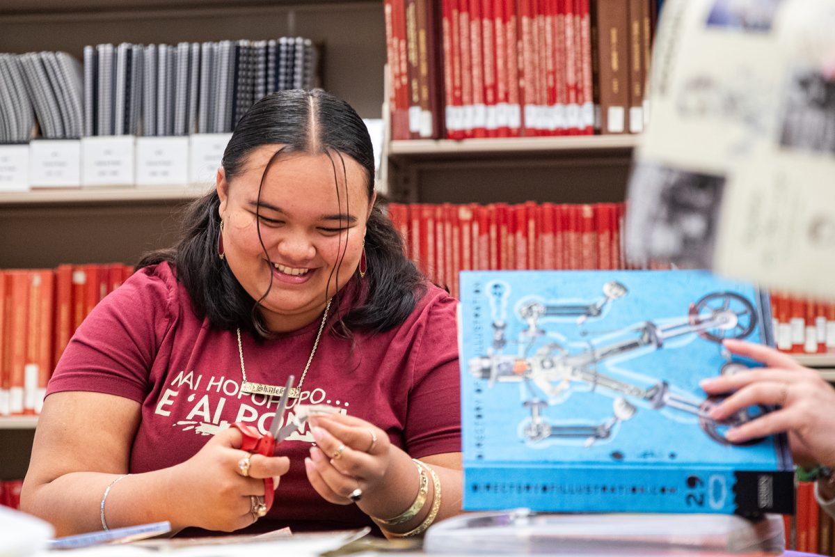 Freshman Shailey Makahanaloa Valoroso cuts material for a collage at the student media information tables during at Library Fest in Ames Library on Thursday, Sept. 21, 2023.