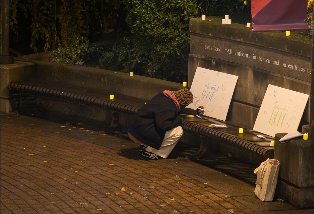 Esther Mutesi adds to the sign asking for people to share words of grief during a candlelight vigil in Martin Square for the victims of the violence that has occurred during the Israel-Palestien conflict. The vigil was held on Tuesday, Nov. 7, 2023, in Seattle.