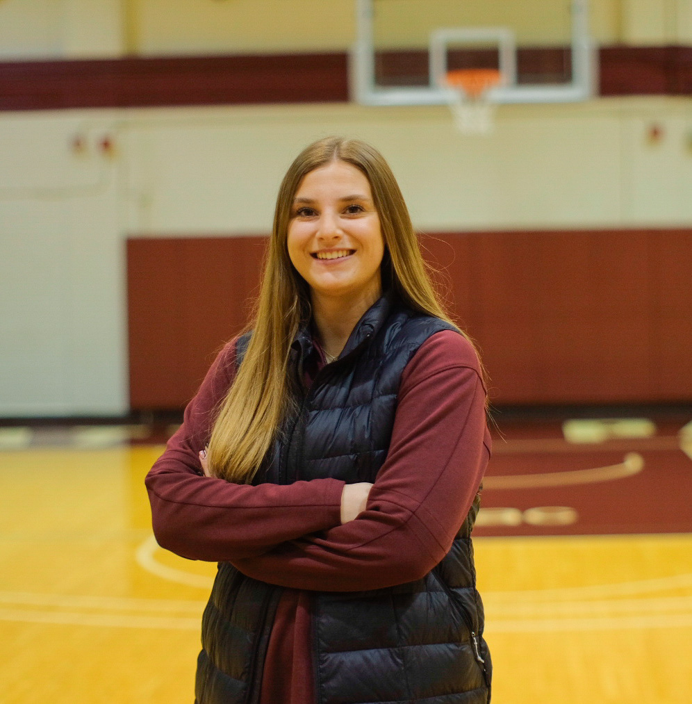 SPU Women's Basketball Assistant Coach Ava Edmonds poses in the main gym of Royal Brougham Pavilion.