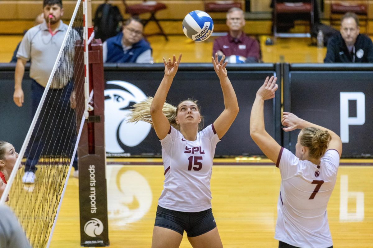 SPU Senior Emily Tulino (15) sets the ball for fellow Falcon Hannah Hair (7) to drive the kill against Western Oregon University.