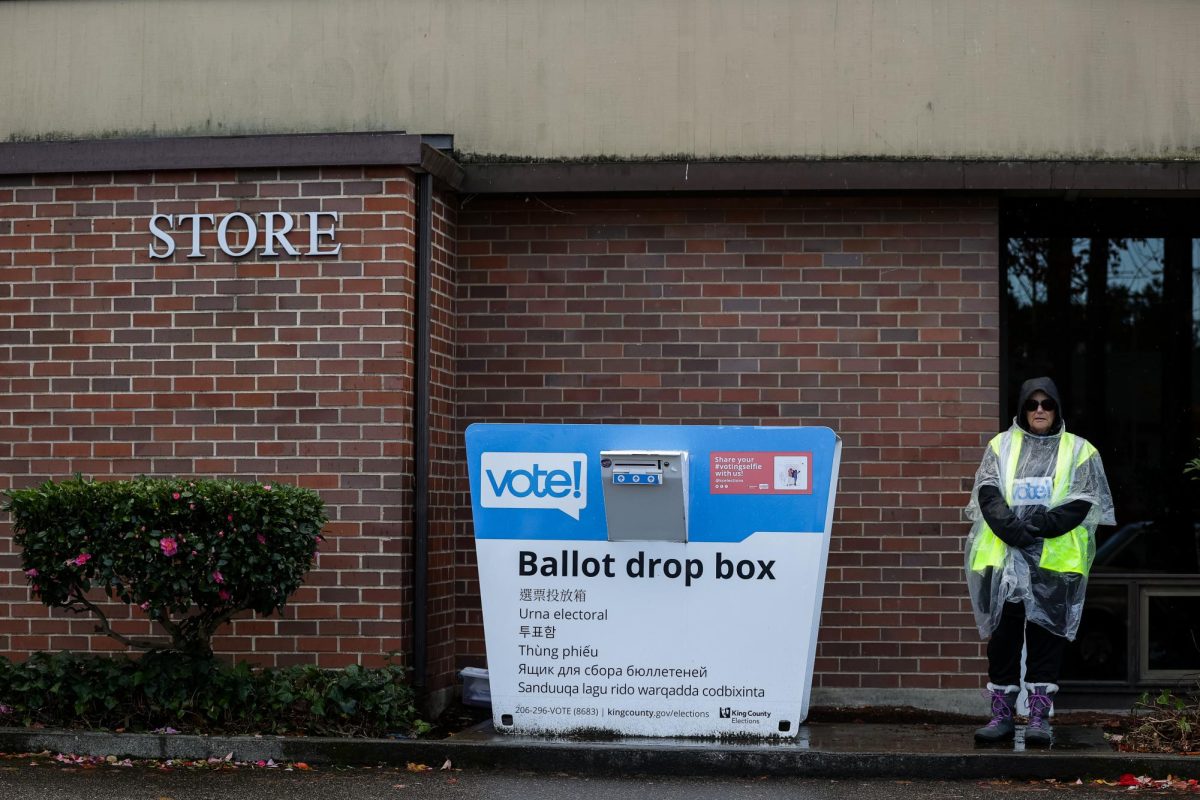 An election worker waits to assist voters at the ballot drop box outside the Seattle Pacific University Bookstore on Tuesday, Nov. 5, 2024, in Seattle.